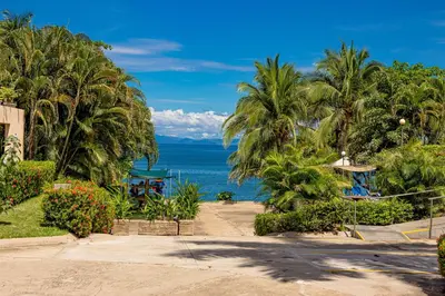 a view of a beach with palm trees and the ocean at Oceanview 3BR Villa with 3 Shared Pools and Beachfront Resort Access in Ocotal