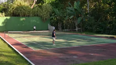 two people playing tennis on a tennis court at Villa Quebrada Estate in Montezuma