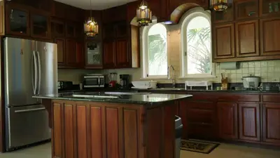 a kitchen with wooden cabinets and a stainless steel refrigerator at Villa Quebrada Estate in Montezuma
