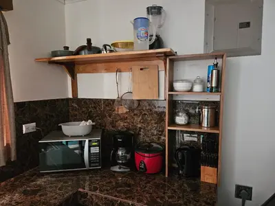 a kitchen with a microwave and a counter with a shelf at Full equipado, WiFi, AC, vista volcán, 1er piso in Fortuna