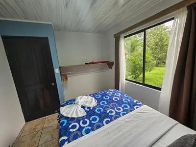 a bedroom with a blue and white bed and a window at Full equipado, WiFi, AC, vista volcán, 1er piso in Fortuna