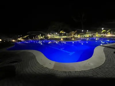 a large pool with blue water at night at Namú Apartment in Herradura