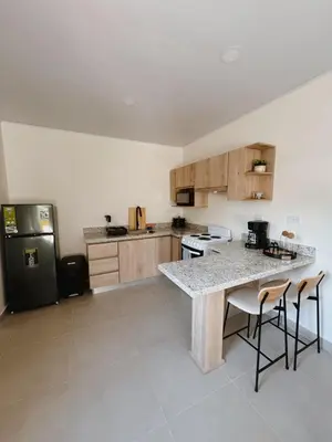 a kitchen with a counter with stools and a refrigerator at Namú Apartment in Herradura