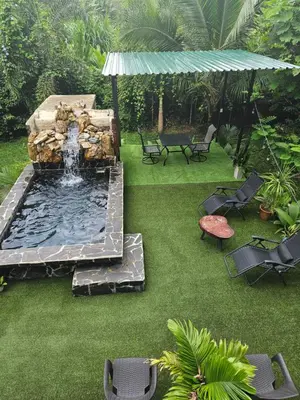 a backyard with a fountain with chairs and a table at ParadiseTropical Garden Cabin with private jacuzzi in Fortuna