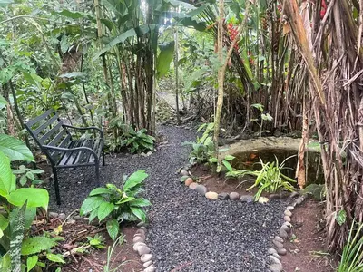 a bench sitting in the middle of a garden at ParadiseTropical Garden Cabin with private jacuzzi in Fortuna