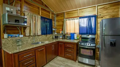 a kitchen with wooden cabinets and a stainless steel refrigerator at ParadiseTropical Garden Cabin with private jacuzzi in Fortuna