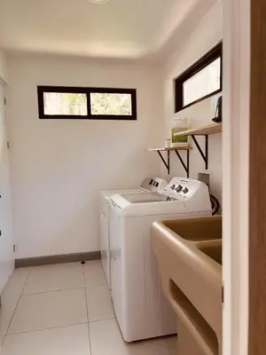 a white laundry room with a washer and a sink at Casa Morfa in Uvita