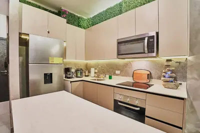 a kitchen with white cabinets and a microwave at Unique Industrial Apt Near Airport in La Sabana in San José