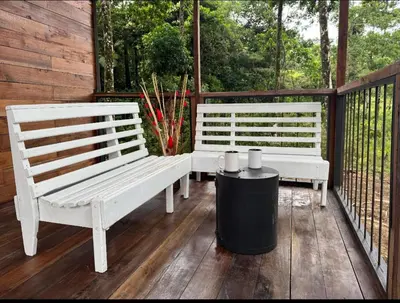 two white benches sitting on a porch with a trash can at Picki's Cabin in Guácimo