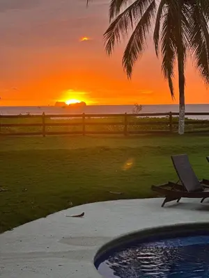 a sunset over the ocean with a bench and a chair at Beachfront2 bed 2 bathPortreroFlamigo-Marina in Playa Flamingo