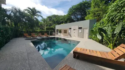 a swimming pool with lounge chairs and a house at Condo Niko - Centrally Located, Steps to Beach! in Tamarindo