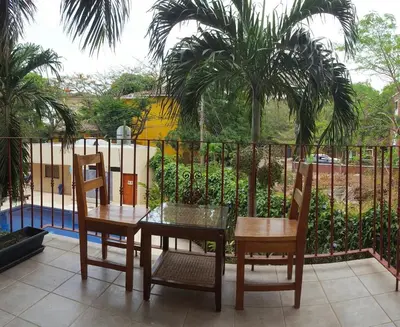 a table and chairs on a balcony with palm trees at Condo Niko - Centrally Located, Steps to Beach! in Tamarindo