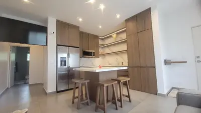 a kitchen with wooden cabinets and a bar with stools at Condo Popeye - Cute condo in the heart of Tama! in Tamarindo