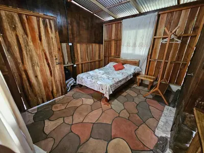 a small room with a bed and a chair in it at Cabaña del Bosque in Tapantí