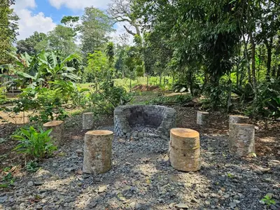 a garden with logs and a fire place at Cabaña del Bosque in Tapantí