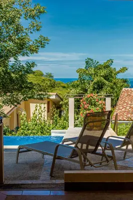 a pair of chairs sitting next to a swimming pool at Romantic 1BR Studio Guesthouse with 3 Shared Pools, Beach and Resort Access in Ocotal