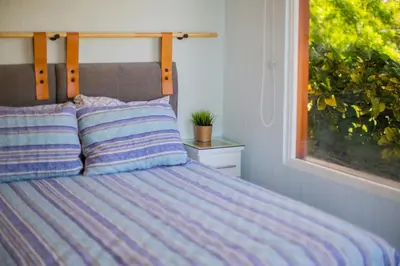 a bed with a striped comforter and a window at Romantic 1BR Studio Guesthouse with 3 Shared Pools, Beach and Resort Access in Ocotal