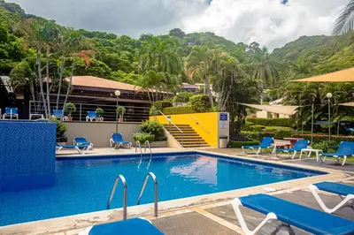 a pool at a resort with blue chairs and a building at Romantic 1BR Studio Guesthouse with 3 Shared Pools, Beach and Resort Access in Ocotal