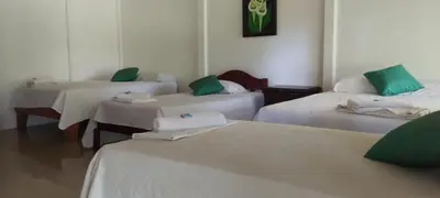 a room with three beds with green and white sheets at Hotel Maguey in Chilamate