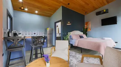 a bedroom with two beds and a kitchen with a table at Refugio Turquesa-Luxury King Suite with Private Jacuzzi Balcony-5 min to La Fortuna in Fortuna