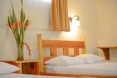 a bedroom with two beds and a vase with a plant at Hotel Cerro Lodge in Tarcoles