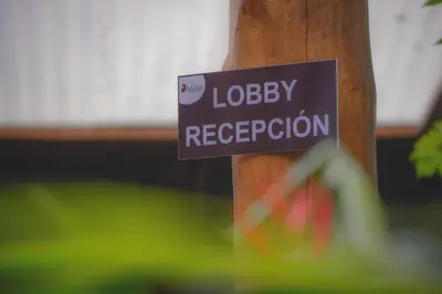 a sign on a pole that reads lobbey reception at Hotel Cerro Lodge in Tarcoles
