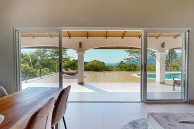 a dining room with a table and sliding glass doors at Eco-Luxurious Villa 4bdr - 5 min to the Beach in Uvita
