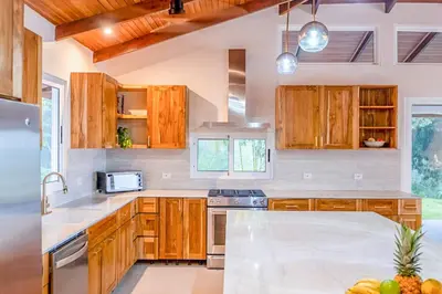 a kitchen with wooden cabinets and a counter top at Eco-Luxurious Villa 4bdr - 5 min to the Beach in Uvita