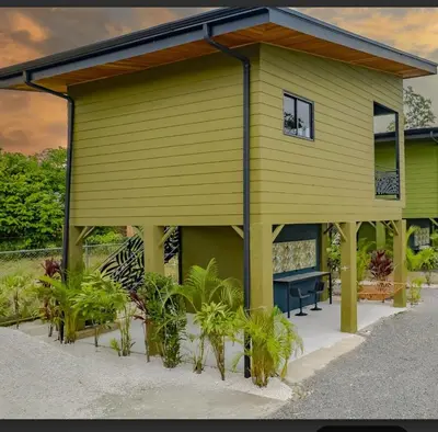 a yellow house with a bench in front of it at Paraiso Lima -Luxury King Suite with Private Jacuzzi Balcony-5 min to La Fortuna in Fortuna
