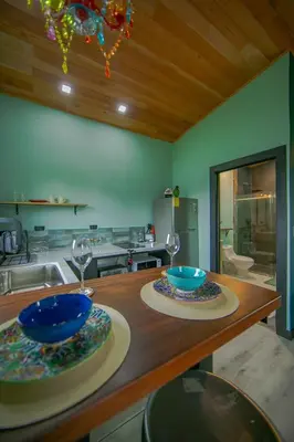 a kitchen with a table with two plates and glasses at Paraiso Lima -Luxury King Suite with Private Jacuzzi Balcony-5 min to La Fortuna in Fortuna