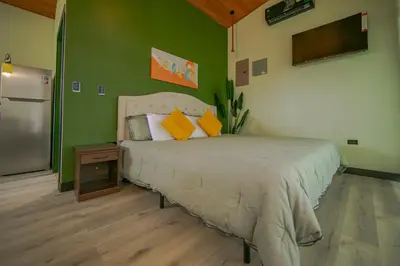 a bedroom with a bed and a green wall at Refugio Verdanza-Luxury King Suite with Private Jacuzzi Balcony-5 min to La Fortuna in Fortuna