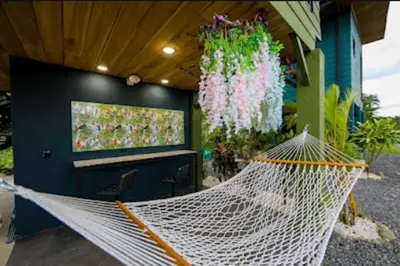 a hammock in a room with a television and flowers at Refugio Verdanza-Luxury King Suite with Private Jacuzzi Balcony-5 min to La Fortuna in Fortuna