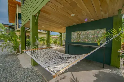 a hammock outside of a house with a building at Refugio Verdanza-Luxury King Suite with Private Jacuzzi Balcony-5 min to La Fortuna in Fortuna