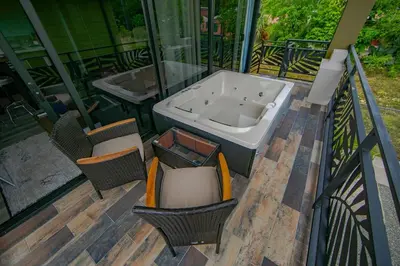 a bath tub sitting on a deck with two chairs at Refugio Verdanza-Luxury King Suite with Private Jacuzzi Balcony-5 min to La Fortuna in Fortuna