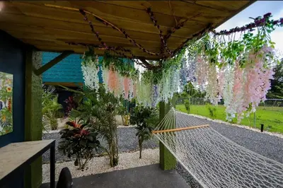 a covered porch with flowers hanging from a pergola at Refugio Verdanza-Luxury King Suite with Private Jacuzzi Balcony-5 min to La Fortuna in Fortuna