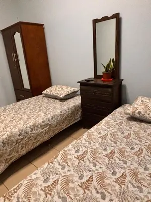 a bedroom with two beds and a dresser with a mirror at El Descanso in Jacó