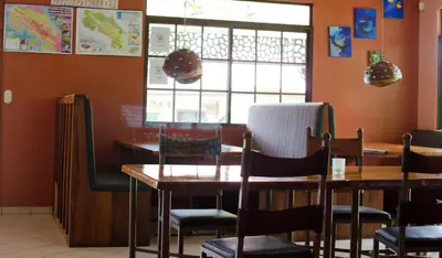 a dining room with tables and chairs and a window at Gingerbread Restaurant & Hotel in Nuevo Arenal