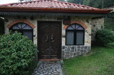 a small stone house with a wooden door at Gingerbread Restaurant & Hotel in Nuevo Arenal