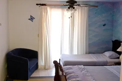 a bedroom with two beds and a chair and a window at Gingerbread Restaurant & Hotel in Nuevo Arenal