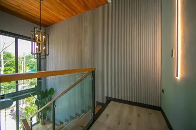 a room with a staircase with a window and a chandelier at La Azulada-5min La Fortuna, King beds, pool, BBQ in Fortuna