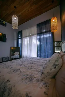 a large bed in a bedroom with two lights at La Azulada-5min La Fortuna, King beds, pool, BBQ in Fortuna