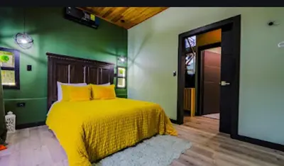 a bedroom with a yellow bed with a green wall at Casa Esmeralda-5min to La Fortuna,King beds & pool in Fortuna