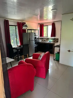a living room with a red couch and a kitchen at Arrecife in Tapantí