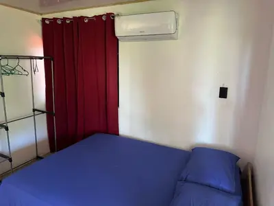 a small bedroom with a blue bed and a red curtain at Arrecife in Tapantí