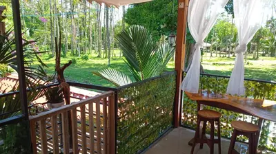 a balcony with a table and stools on a porch at Arrecife in Tapantí