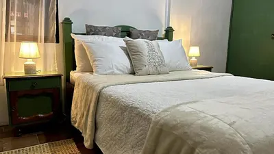 a bedroom with a large bed with white sheets and pillows at Casita Vintage AC in Turrialba