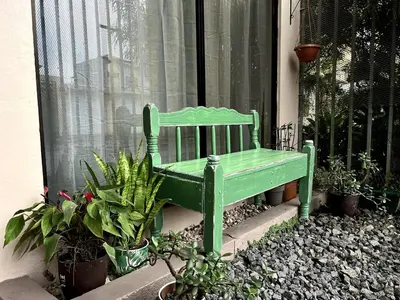 a green bench sitting in front of a window at Casita Vintage AC in Turrialba