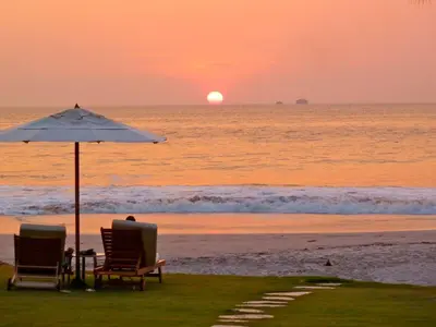 two chairs and an umbrella on the beach at sunset at Apartment located in The Palms Private in Playa Flamingo, Costa Rica in Portegolpe