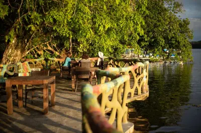a group of people sitting at tables by the water at Laguna Lodge Full Board in Tortuguero