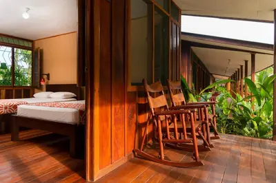 a room with a bed and two rocking chairs in it at Laguna Lodge Full Board in Tortuguero